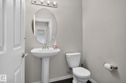 Powder room featuring a pedestal sink, oval mirror, brushed nickel hardware, and wood-finish flooring - 