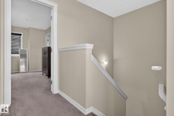 Upper-level hallway featuring neutral wall paint, white trim, and plush carpet flooring - 