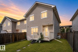 Rear exterior featuring tan horizontal siding, a private fenced yard with a grass lawn, and a back deck with white railings - 