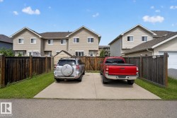 Concrete driveway providing off-street parking, bordered by wood fencing and a grass strip - 