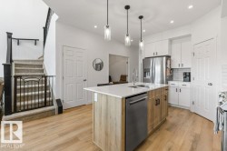 Modern kitchen featuring a central island with a built-in sink and stainless steel dishwasher - 