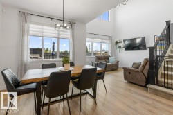 Open-concept living space featuring wood-finish flooring, a two-story ceiling, and a prominent staircase with metal balusters - 