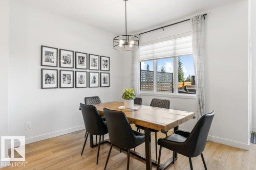 Dining area featuring wood-finish flooring, a contemporary chandelier, and a large window - 25 Nettle Crescent, St. Albert, AB 