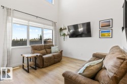 Open concept living space featuring wood-finish flooring, large windows, and high ceilings - 