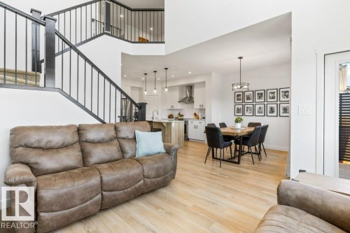 Open concept main level featuring light wood-finish flooring, a contemporary staircase with black railings, and white walls - 25 Nettle Crescent, St. Albert, AB 