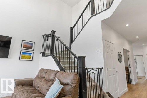 Two-story entryway with high ceilings and a carpeted staircase featuring black railings - 25 Nettle Crescent, St. Albert, AB 