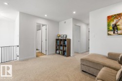 Spacious carpeted landing featuring recessed lighting, white walls, and a black metal railing - 
