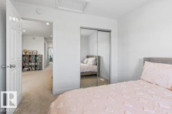 Interior bedroom featuring a sliding mirrored closet door, white walls, and a light-colored carpeted floor - 