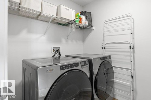Dedicated laundry area featuring a washer and dryer, elevated wire shelving, and light-toned walls - 25 Nettle Crescent, St. Albert, AB 