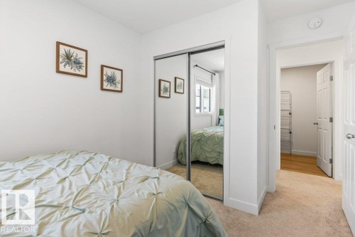 Bedroom featuring a mirrored sliding closet door, white walls, and light beige carpet - 25 Nettle Crescent, St. Albert, AB 