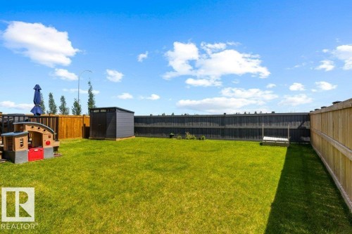 Expansive backyard featuring a manicured lawn, a grey storage shed, and a privacy fence - 25 Nettle Crescent, St. Albert, AB 