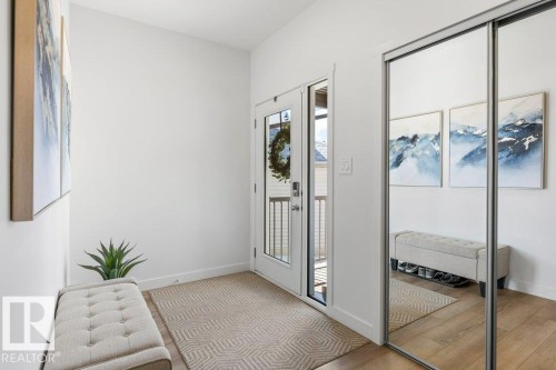 Entryway featuring a glass-paneled door, light wood-finish flooring, and a mirrored sliding closet door - 25 Nettle Crescent, St. Albert, AB 