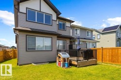 Expansive green lawn with a wooden privacy fence surrounding a raised deck featuring black railings - 