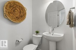 Pedestal sink with chrome faucet, oval mirror, and white toilet - 