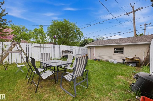 Expansive backyard featuring a white picket fence, a detached garage with a side entry door, and mature trees - 8911 169 Street Nw, Edmonton, AB 