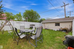 Expansive backyard featuring a white picket fence, a detached garage with a side entry door, and mature trees - 