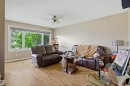 Spacious room featuring wood-finish flooring, a large multi-pane window, and a ceiling fan with integrated lighting - 8911 169 Street Nw, Edmonton, AB 