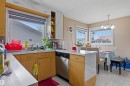 Kitchen and dining area featuring a double basin stainless steel sink, wood-finish cabinetry, light-toned countertops, and tiled flooring - 8911 169 Street Nw, Edmonton, AB 