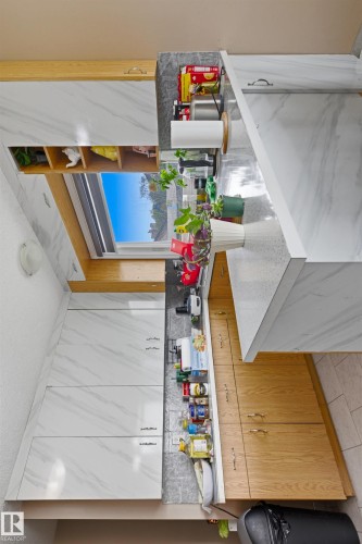 Contemporary kitchen featuring white wood-finish cabinetry with linear pulls, light wood-finish lower cabinetry, and light-toned countertop surfaces - 8911 169 Street Nw, Edmonton, AB 