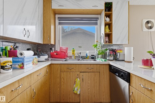 U-shaped kitchen layout featuring wood-finish lower cabinetry, white marbled upper cabinetry, and a light-toned countertop - 8911 169 Street Nw, Edmonton, AB 