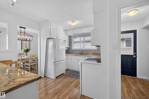 Kitchen featuring white cabinetry, wood-finish flooring, and a stone-look countertop - 244 Knottwood Road N, Edmonton, AB 