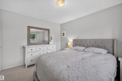 Bedroom featuring textured carpeting, light gray walls, a ceiling-mounted light fixture, and a window with white blinds - 