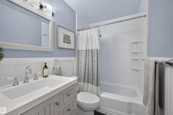 Bathroom featuring a light blue wall color, white wainscoting, and a white vanity with a rectangular sink - 
