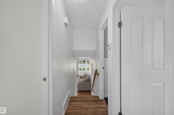Bright interior hallway featuring light-colored walls and wood-finish flooring - 