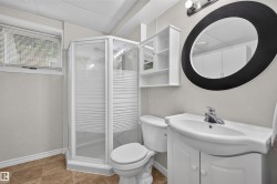 Three-piece bathroom featuring a corner shower with a glass enclosure, a white vanity with an integrated sink, a wall-mounted storage cabinet, and a large oval mirror - 
