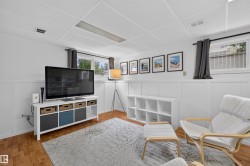 Finished living space featuring wood-finish flooring, white paneling, and a drop ceiling with integrated lighting - 