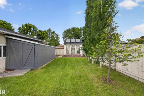 Expansive backyard featuring a green lawn, wood fence, and mature trees - 244 Knottwood Road N, Edmonton, AB 