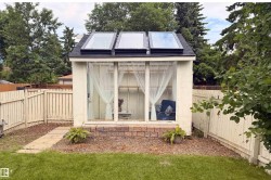 Detached accessory building featuring multiple skylights, extensive window panels, and a brick-finish foundation - 