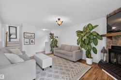 Living area featuring wood-finish flooring, a stone-faced fireplace with a hearth, and white walls - 