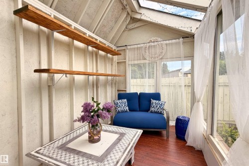 Sunroom featuring wood-finish flooring, a skylight, and large window panels - 244 Knottwood Road N, Edmonton, AB 