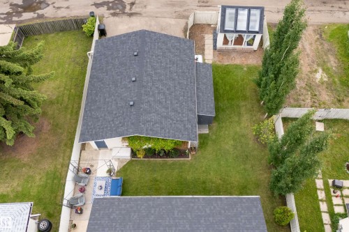 Expansive property showcasing a main residence with a dark shingle roof, a detached structure with a transparent roof, manicured lawns, mature trees, and a paved patio area - 244 Knottwood Road N, Edmonton, AB 
