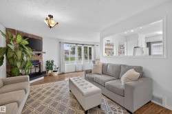 Living area featuring wood-finish flooring and a stone-clad fireplace with a black mantel - 