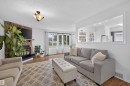 Living area featuring wood-finish flooring and a stone-clad fireplace with a black mantel - 244 Knottwood Road N, Edmonton, AB 
