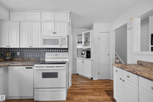 Kitchen featuring white cabinetry with contrasting hardware and patterned backsplash - 244 Knottwood Road N, Edmonton, AB 