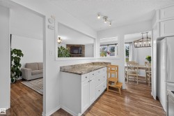 Functional kitchen with white cabinetry and wood-finish flooring - 