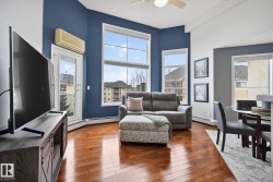 Living area featuring wood-finish flooring, a ceiling fan, and abundant natural light from large windows - 