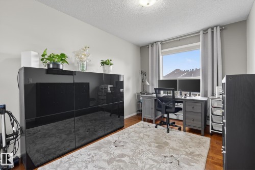 Room featuring wood-finish flooring, a window with grey curtains, and neutral wall paint - 421 9730 174 Street, Edmonton, AB 