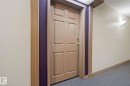 Panel door with gold-finish hardware, framed by fluted trim and a purple accent wall - 421 9730 174 Street, Edmonton, AB 