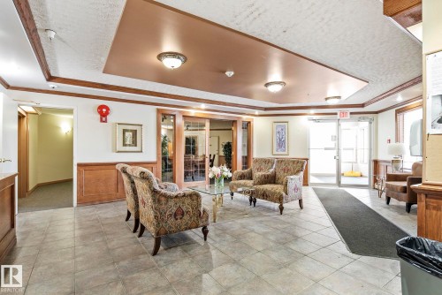 Tiled entryway featuring a tray ceiling with recessed lighting, wood-paneled walls, and double glass doors - 421 9730 174 Street, Edmonton, AB 