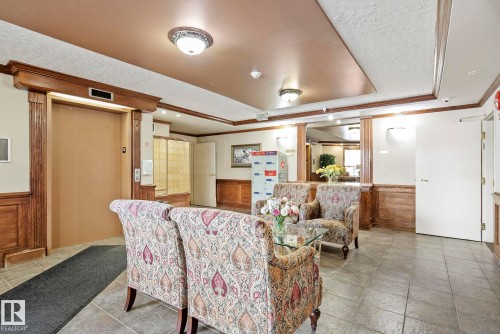 Lobby area featuring tiled flooring, wood-paneled walls, and architectural wood trim - 421 9730 174 Street, Edmonton, AB 