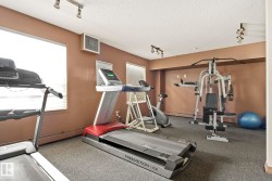 Fitness area featuring track lighting, windows with blinds, and neutral-toned wall paint - 