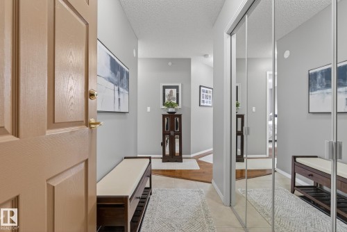 Foyer featuring light gray walls, wood-finish flooring, mirrored closet doors, and recessed lighting - 421 9730 174 Street, Edmonton, AB 
