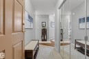 Foyer featuring light gray walls, wood-finish flooring, mirrored closet doors, and recessed lighting - 421 9730 174 Street, Edmonton, AB 
