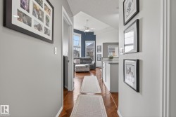Hallway featuring light gray walls, wood-finish flooring, and white baseboards - 