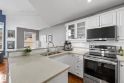 Kitchen featuring white cabinetry, light-toned countertops, stainless steel appliances, and wood-finish flooring - 