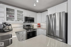 Kitchen featuring white shaker cabinetry, stainless steel appliances, light-toned countertops, and a subway tile backsplash with decorative accent - 
